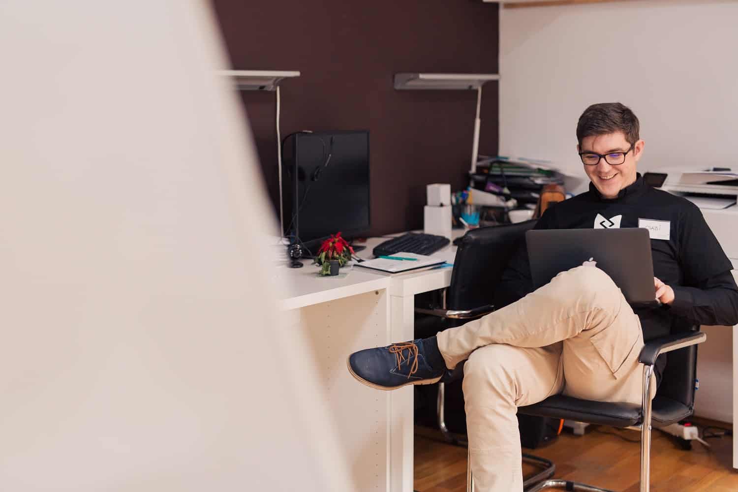 college student sitting in dorm room on a laptop smiling