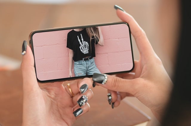 Woman taking picture of t-shirt to list on Poshmark